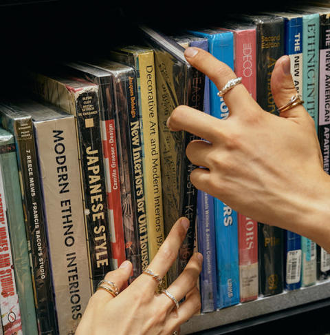 Chapters bookstoreのオリジナルリングを着けた手と手が、本棚で重なり合うイメージ